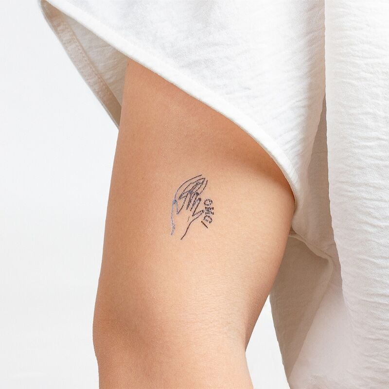 Minimalist line art tattoo of folded hands on inner arm.