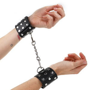 KINK - WRIST RESTRAINTS WITH SNAP FASTEN FULL OF RIVETS BLACK ADJUSTABLE 19-24 CM X 5.5 CM - LoveYou.lv