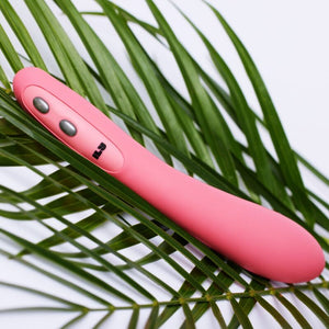 Pink Je Joue G-Spot Vibrator with dual button design, lying on green leaves, offering sleek and powerful vibrations for intimate pleasure.