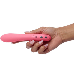 Hand holding JE JOUE pink G-spot vibrator with sleek design and optional warm setting for enhanced pleasure.